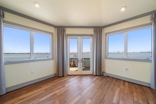 unfurnished room featuring wood-type flooring, a water view, and crown molding