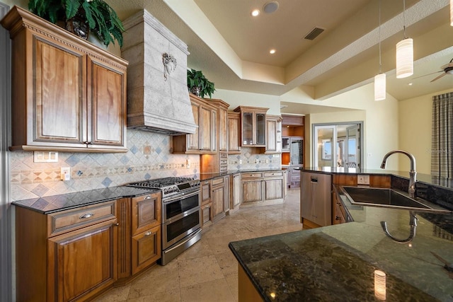 kitchen featuring pendant lighting, sink, premium range hood, stainless steel appliances, and decorative backsplash