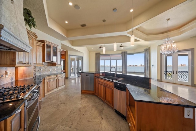 kitchen featuring sink, hanging light fixtures, a raised ceiling, a water view, and a spacious island