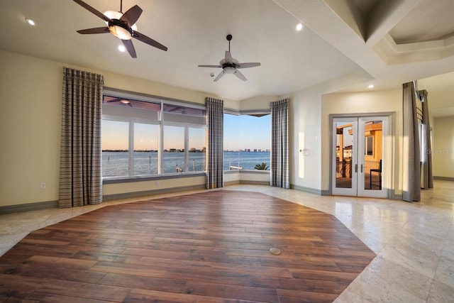 empty room with wood-type flooring, a water view, ceiling fan, and french doors