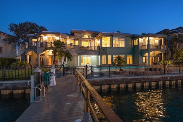 rear view of property with a water view, a balcony, a fenced in pool, and a patio area