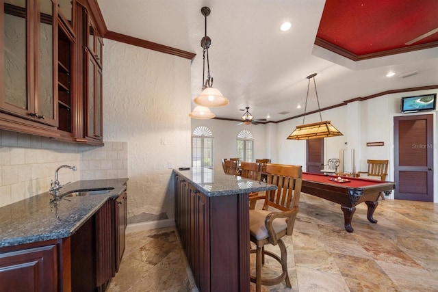 kitchen featuring glass insert cabinets, a peninsula, ornamental molding, a sink, and baseboards