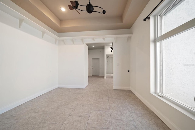 empty room with baseboards, a raised ceiling, a chandelier, recessed lighting, and light tile patterned flooring
