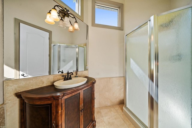 full bath featuring a shower stall, vanity, tile patterned flooring, a wainscoted wall, and tile walls