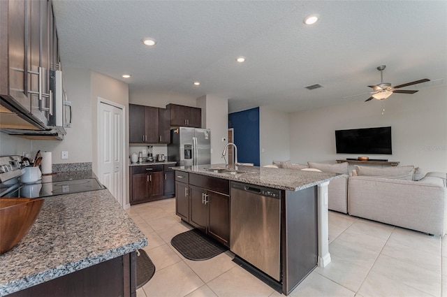 kitchen featuring appliances with stainless steel finishes, an island with sink, sink, light tile patterned floors, and dark brown cabinetry