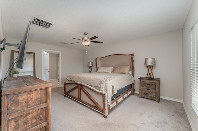 bedroom with ceiling fan, light colored carpet, and a textured ceiling