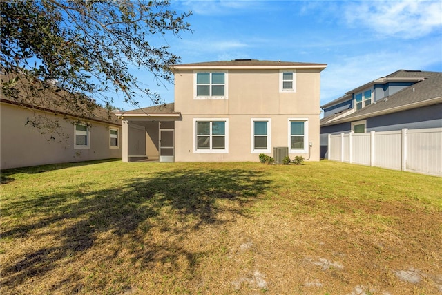 rear view of property with cooling unit, a sunroom, and a lawn