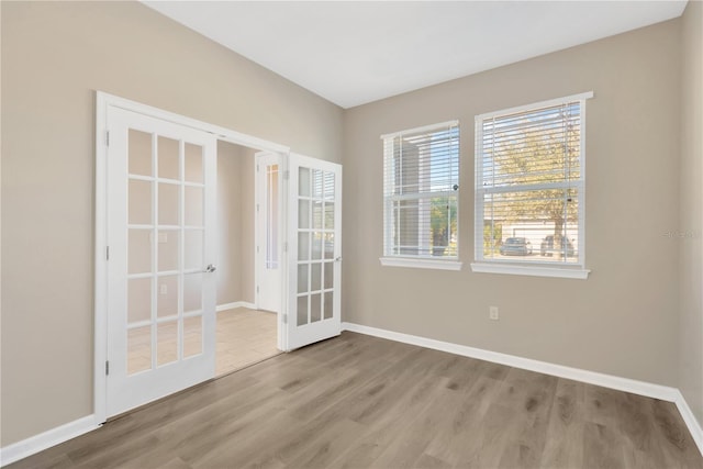 empty room with light hardwood / wood-style floors and french doors