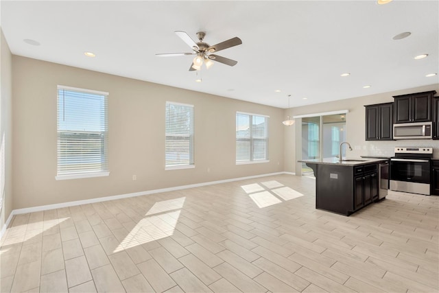 kitchen featuring appliances with stainless steel finishes, sink, a kitchen island with sink, and ceiling fan