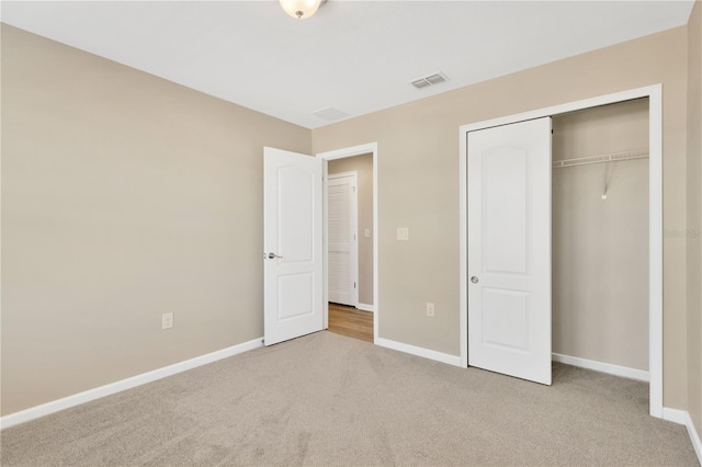 unfurnished bedroom featuring light carpet and a closet