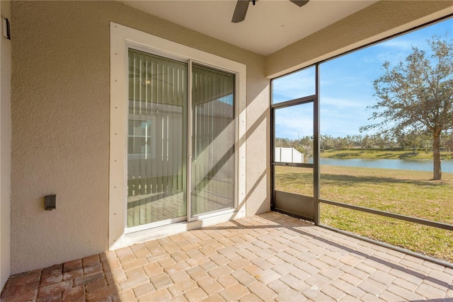 unfurnished sunroom with a water view and ceiling fan