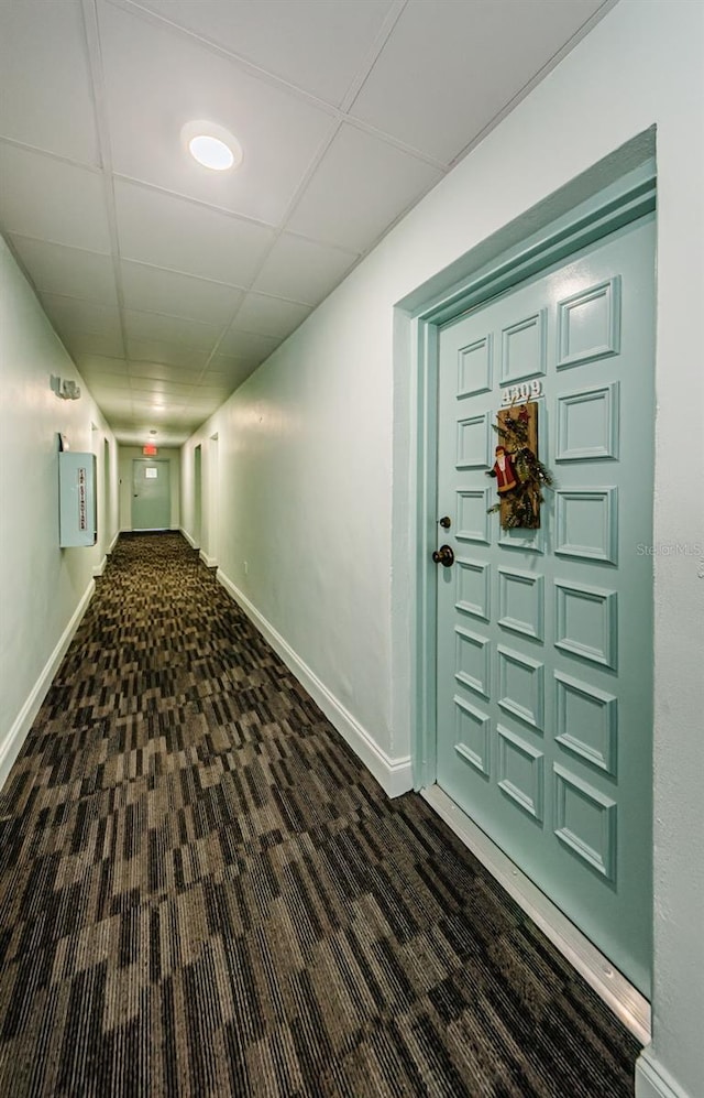 corridor featuring dark colored carpet and a paneled ceiling