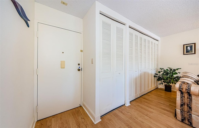 corridor with a textured ceiling and light hardwood / wood-style floors