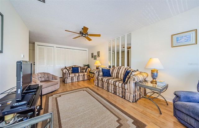 living room with wood-type flooring, ceiling fan, and a textured ceiling