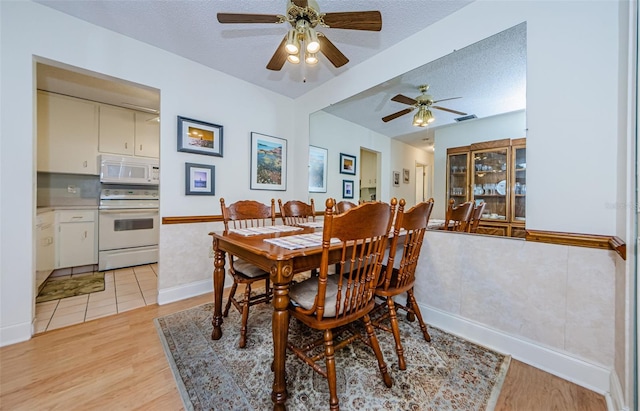 dining space featuring ceiling fan, a textured ceiling, and light wood-type flooring