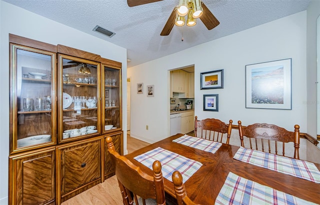 dining room featuring ceiling fan, a textured ceiling, and light wood-type flooring