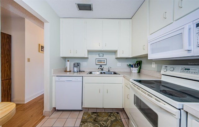 kitchen featuring sink, white appliances, light tile patterned floors, a textured ceiling, and white cabinets