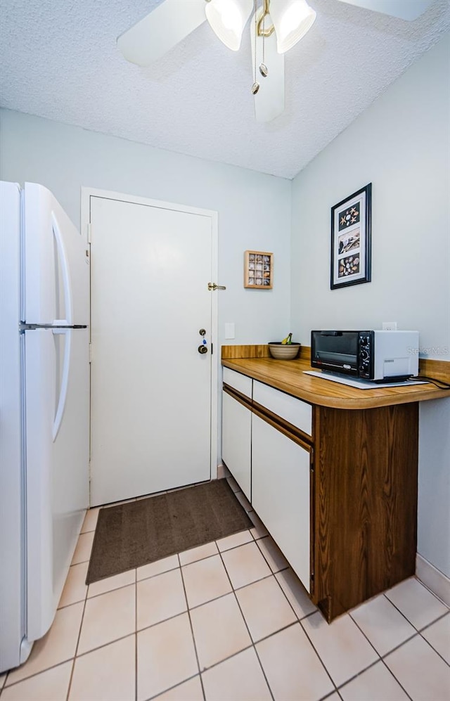 kitchen featuring light tile patterned floors, a textured ceiling, ceiling fan, and white fridge