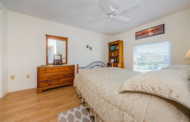 bedroom with ceiling fan, a textured ceiling, and light hardwood / wood-style floors