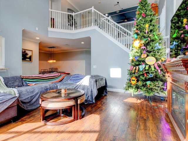 bedroom with hardwood / wood-style flooring, ornamental molding, and a towering ceiling