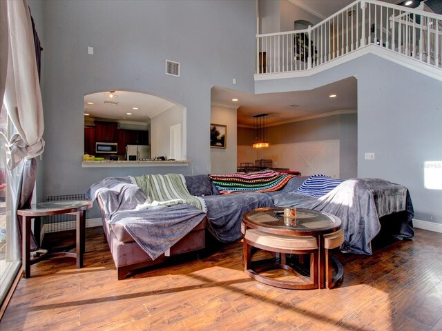 interior space with crown molding, a towering ceiling, and hardwood / wood-style floors