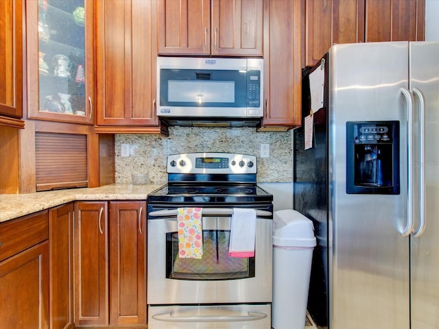 kitchen featuring light stone counters, backsplash, and stainless steel appliances