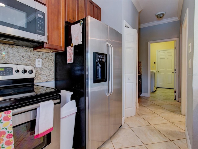 kitchen featuring light tile patterned floors, crown molding, appliances with stainless steel finishes, washer / clothes dryer, and decorative backsplash