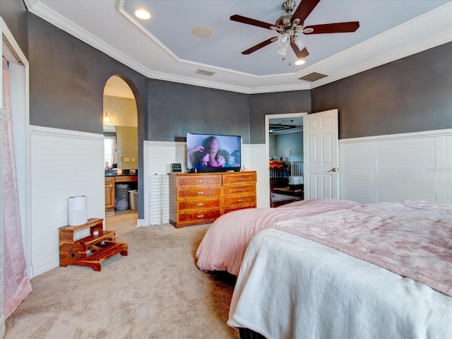 bedroom featuring crown molding, connected bathroom, light colored carpet, and ceiling fan