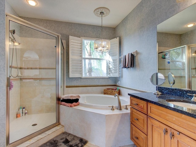 bathroom featuring independent shower and bath, vanity, and a notable chandelier