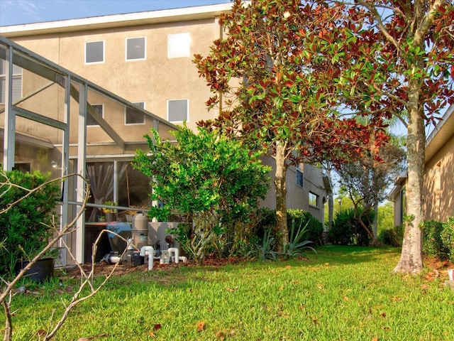 rear view of property featuring glass enclosure and a lawn