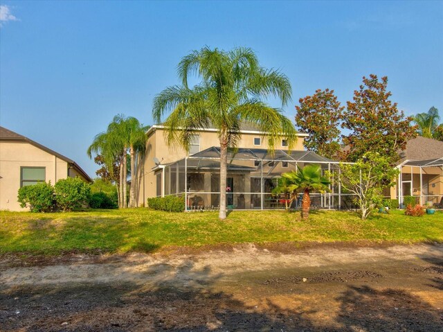 back of house with a yard and a lanai