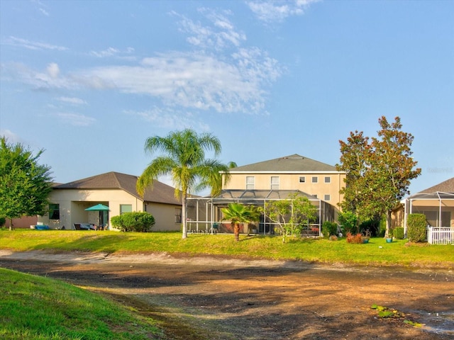 view of front of home featuring glass enclosure and a front lawn