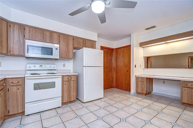 kitchen with ceiling fan, white appliances, built in desk, and a textured ceiling