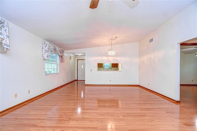 spare room with ceiling fan, lofted ceiling, a textured ceiling, and light hardwood / wood-style floors