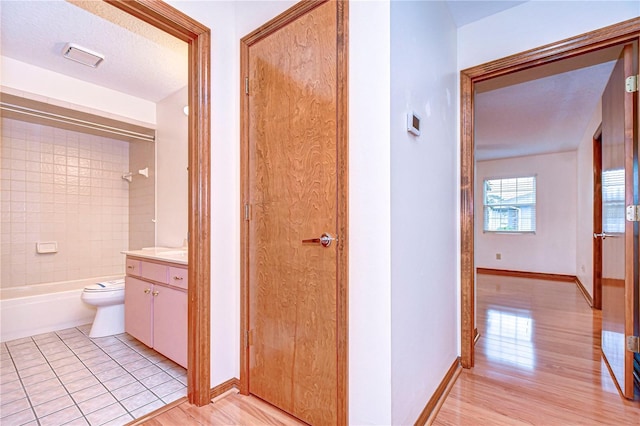 full bathroom featuring tiled shower / bath, hardwood / wood-style flooring, vanity, toilet, and a textured ceiling