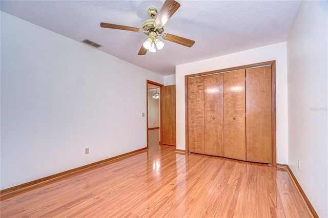 unfurnished bedroom featuring a closet, ceiling fan, a textured ceiling, and light hardwood / wood-style flooring