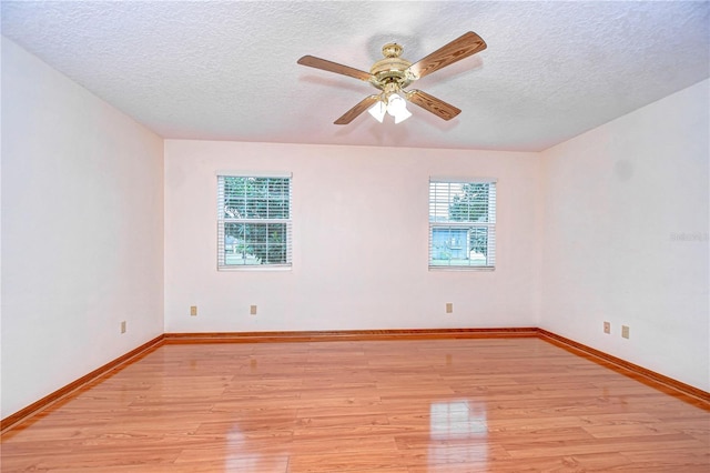 spare room featuring a textured ceiling, a wealth of natural light, light hardwood / wood-style floors, and ceiling fan