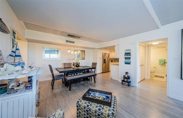 dining area with wood-type flooring, ornamental molding, and a textured ceiling