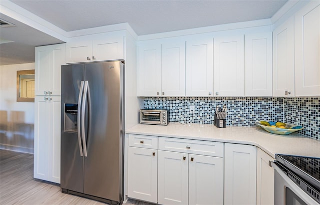 kitchen with white cabinetry, stainless steel fridge, decorative backsplash, and light wood-type flooring