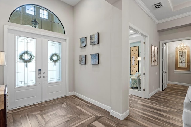 foyer with crown molding, dark parquet flooring, and french doors