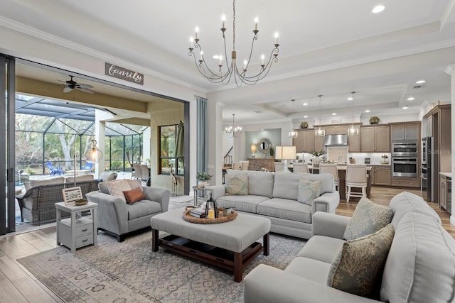 living room featuring a tray ceiling, light hardwood / wood-style flooring, ornamental molding, and ceiling fan