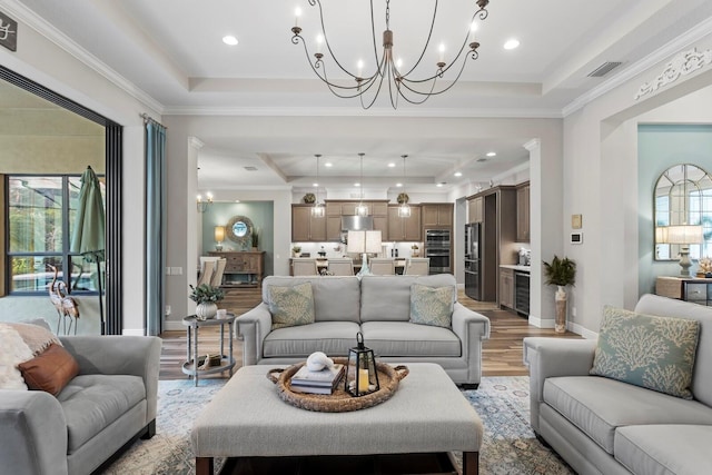 living room with a raised ceiling, ornamental molding, and plenty of natural light