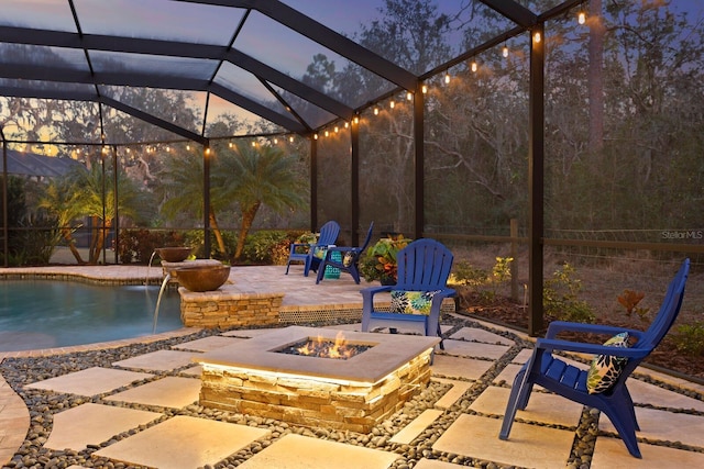 patio terrace at dusk with a lanai, pool water feature, and a fire pit