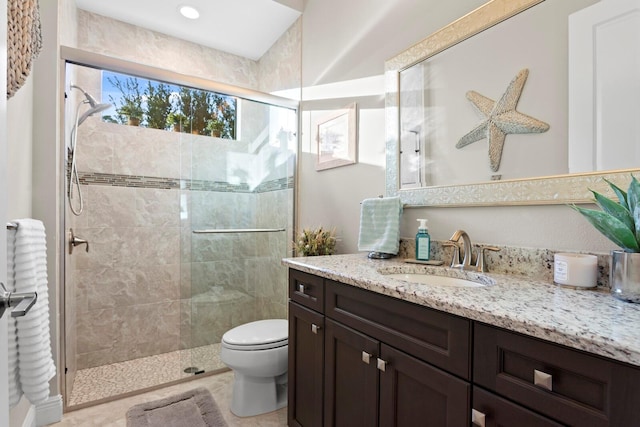 bathroom featuring vanity, a shower with door, and toilet