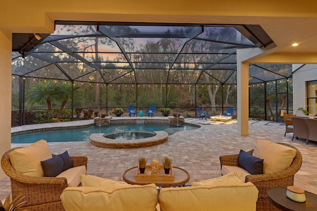 pool at dusk featuring a patio, an in ground hot tub, pool water feature, an outdoor hangout area, and glass enclosure