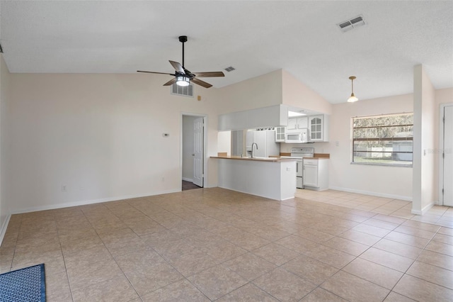 unfurnished living room featuring ceiling fan, sink, vaulted ceiling, and light tile patterned floors