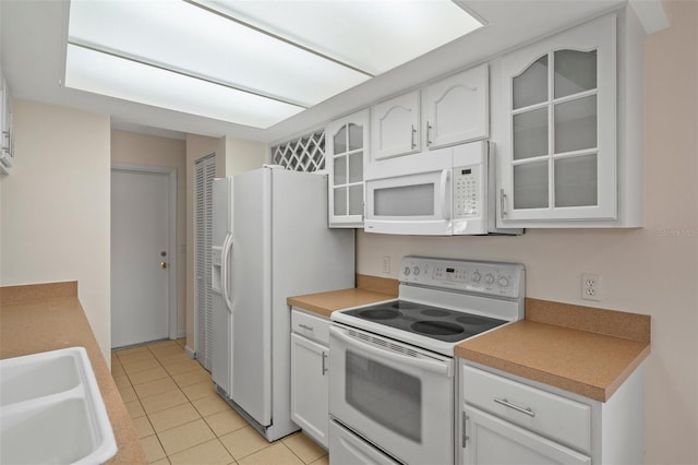 kitchen featuring white cabinetry, sink, light tile patterned floors, and white appliances