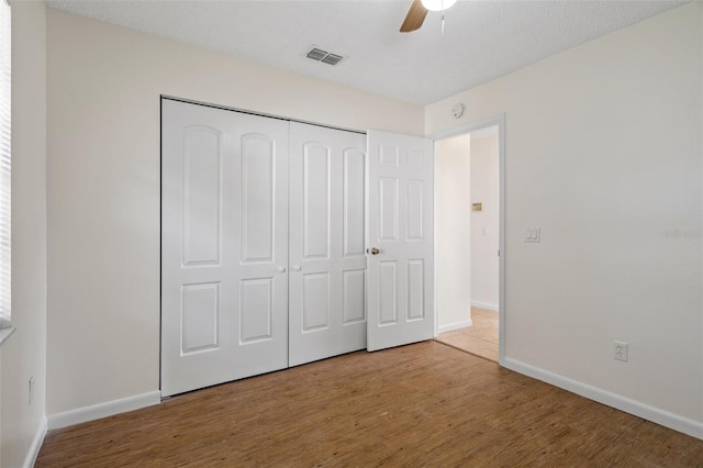 unfurnished bedroom with hardwood / wood-style floors, ceiling fan, and a closet