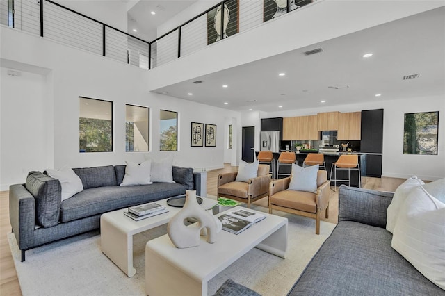 living room with a towering ceiling, plenty of natural light, and light hardwood / wood-style floors