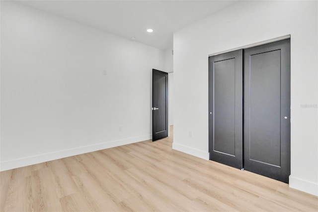 unfurnished bedroom with a closet and light wood-type flooring